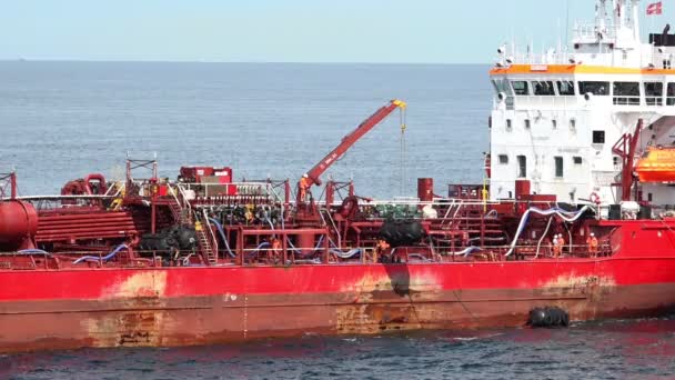 Old Red Oil tanker Crane sätter svart luft fat ner till vatten — Stockvideo