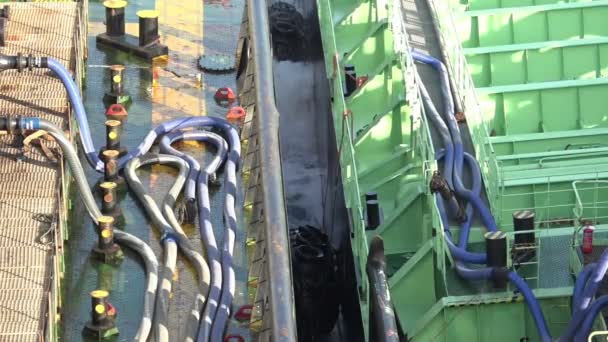 Black safety barrels between green and brown oil tankers — Stock Video