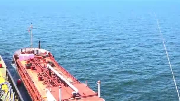 Czerwony zbiornikowiec z białą rurą żagle z dala od dużego naczynia — Wideo stockowe