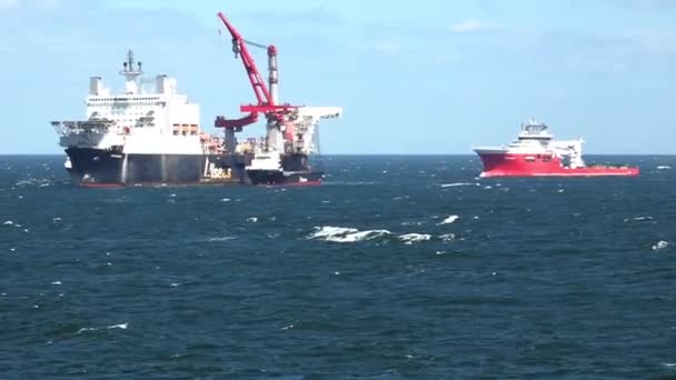 Navire rouge vogue derrière le navire de levage lourd moderne en haute mer — Video