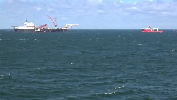 Красно-белое судно отплывает за современным тяжелым подъемником — стоковое видео