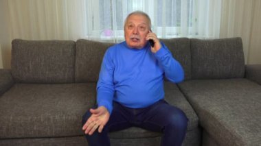 adam kahverengi kanepeüzerinde oturur siyah cep telefonu tutar ve görüşmeler
