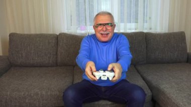 venturous yaşlı adam video oyunu oynarken konsol düğmelerine basAr