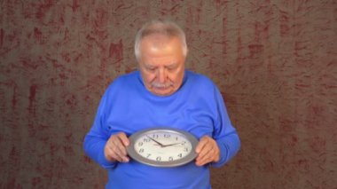 yaşlı adam duvar kağıdı karşı durur saat tutar ve sevinir