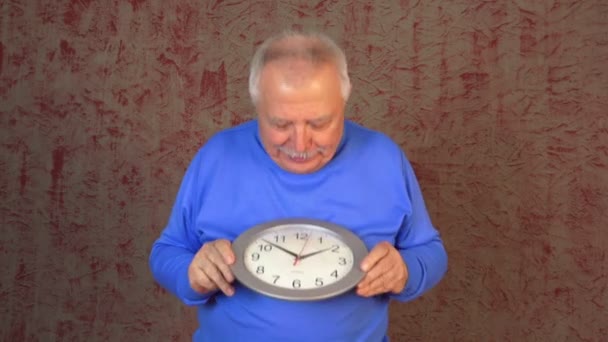 Old man håller modern silver Wall Clock looks och blir upprörd — Stockvideo