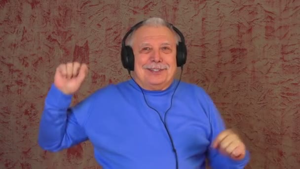 Homem idoso com dentes perfeitos em fones de ouvido sorrisos dançando — Vídeo de Stock