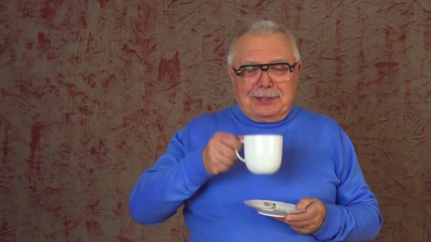 Пожилой человек в очках стоит и наслаждается капучино — стоковое видео