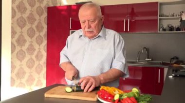 konsantre kıdemli adam gemide yavaş yavaş yeşil salatalık keser