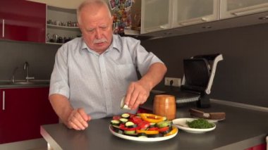 beyaz gömlekli kıdemli adam sebze üzerine zeytinyağı döker