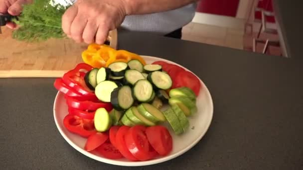 Старший берет свежий укроп из тарелки с овощами — стоковое видео