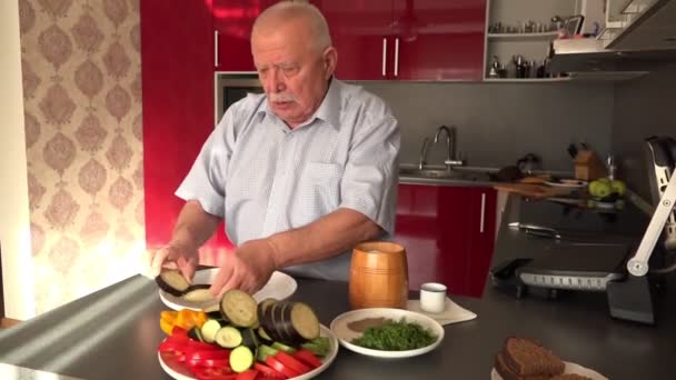 Hombre mayor con bigote pone berenjena en plato blanco — Vídeo de stock