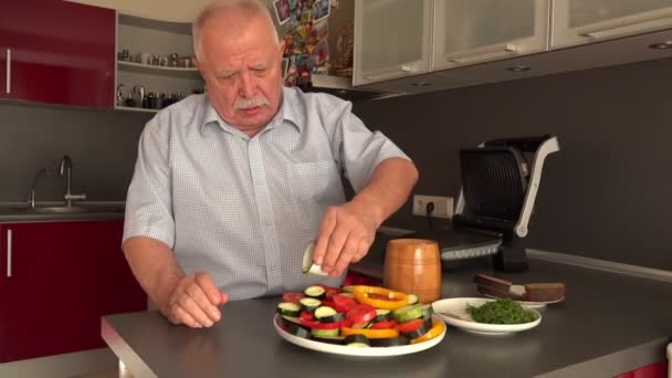 Starší muž v bílé košili nalévá olivový olej na zeleninu — Stock video