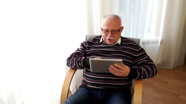 Man sits in armchair and has fun showing tab green screen — Stock Video