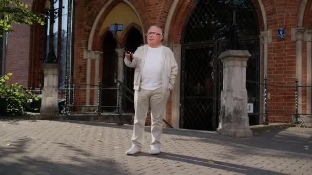Volwassen man in glazen maakt selfie bij oude bakstenen gebouw — Stockvideo