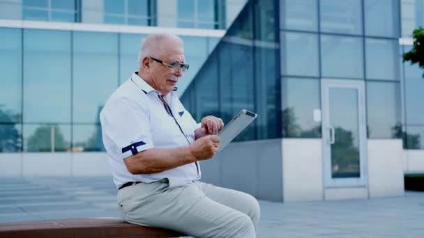 Homme mature avec tablette se trouve sur le banc au centre de bureau moderne — Video