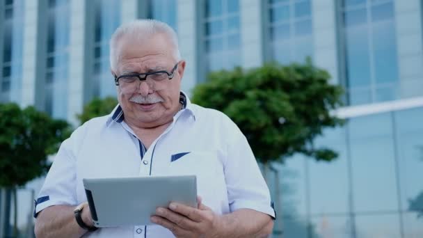 Pensionista utiliza tableta contra edificio de oficinas en el centro de — Vídeos de Stock