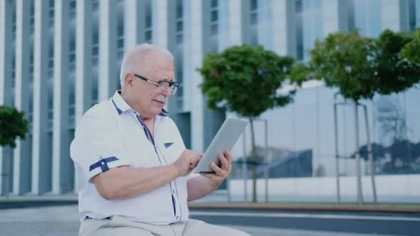 Pensioner usa tablet sentado no banco na rua da cidade — Vídeo de Stock