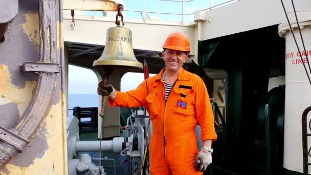 Sorrindo bosun anéis grande relógio sino no convés petroleiro — Vídeo de Stock