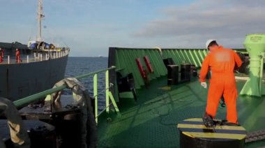 Tanker Onyx Bosun turuncu koruyucu giysiyle ip atıyor.