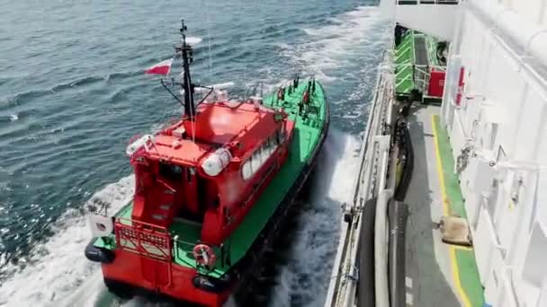 Red pilot motorboat moors to large tanker Onyx board — стокове відео