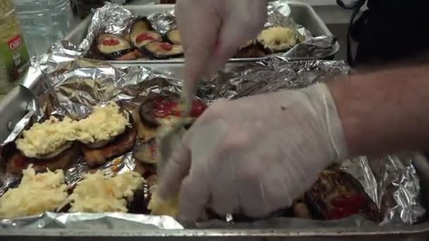 Koch in weißen Handschuhen legt geriebenen Käse auf Auberginenscheiben — Stockvideo