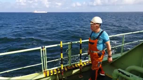 Uomo anziano in tuta cammina via lungo ponte petroliera — Video Stock