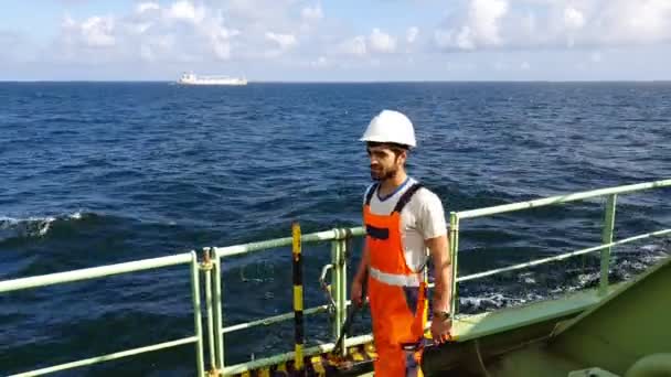 Trabajador barbudo camina a lo largo de cubierta petrolera verde sonriendo — Vídeo de stock