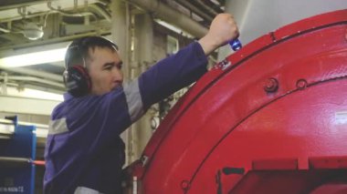 Kulaklıkta yetenekli tamirci tanker ekipmanlarını tamir ediyor.