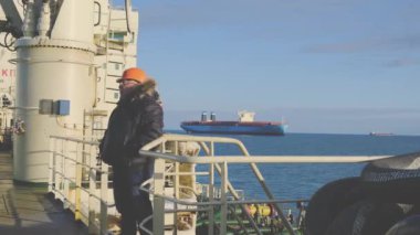 Kamera operatörü konteynır gemisine karşı tanker boyunca yürüyor