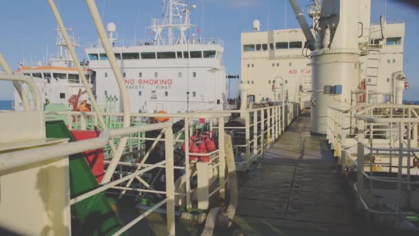 Видеооператор в специальном оранжевом шлеме идет вдоль танкера — стоковое видео