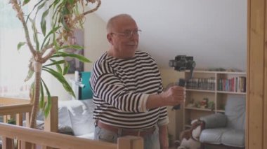 Adam elinde akıllı telefonla tripodu tutuyor ve video çekiyor.
