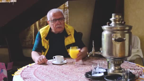 Homem gosta de beber suco de laranja fresco sentado à mesa — Vídeo de Stock