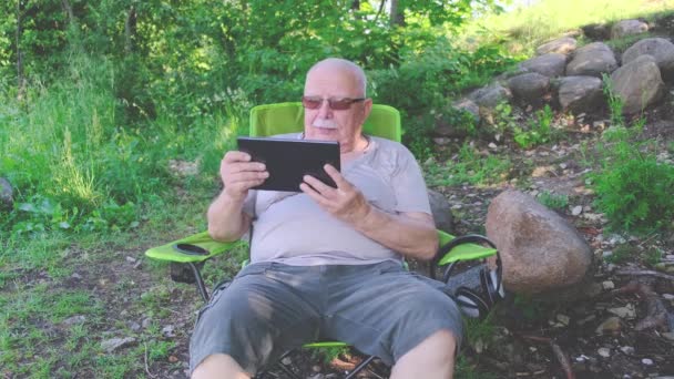 Συνταξιούχος φαλακρός άνδρας κάθεται χαλαρός στην πολυθρόνα κρατώντας καρτέλα — Αρχείο Βίντεο