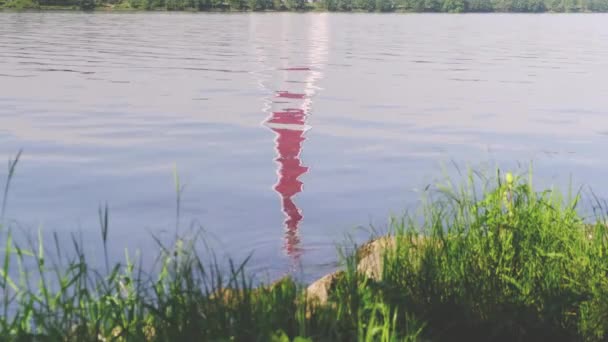 Alto faro rosso riflette in acqua di fiume ancora blu — Video Stock