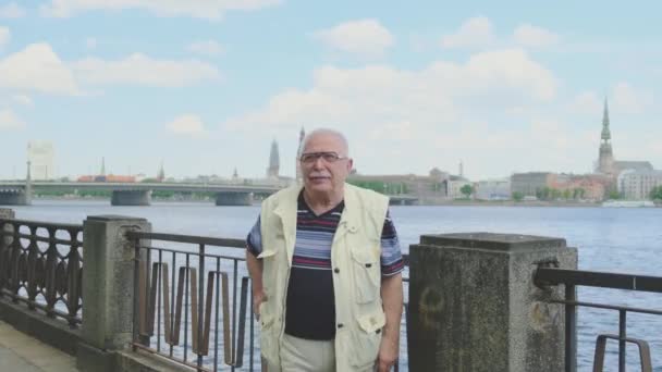 Nyugdíjas kéz a kézben jár a kamera felé a folyóparton — Stock videók