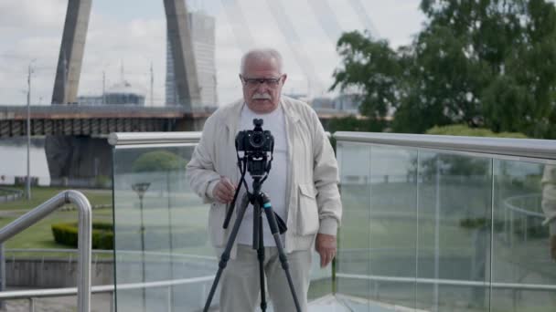 Ανώτερος άνθρωπος με κάμερα σε τρίποδο συνομιλίες στην οδό της πόλης — Αρχείο Βίντεο