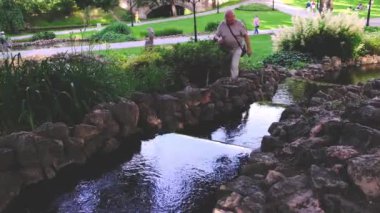 Emekli adam çalıların ve dar derelerin yanında yürüyor.