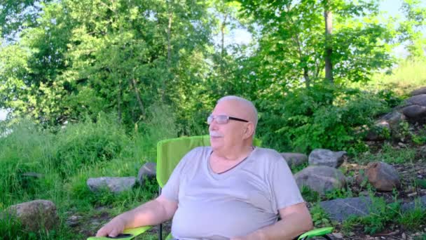 Důchodce sedí v křesle a má teplé počasí — Stock video