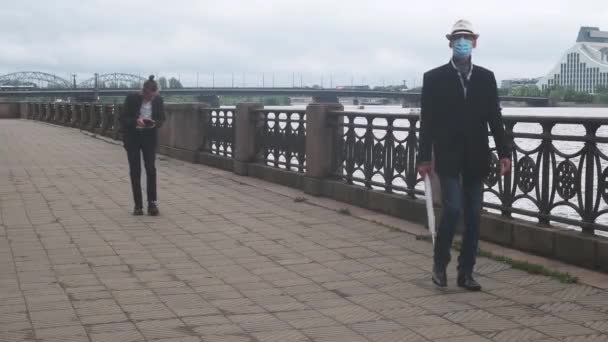 Homem sênior em máscara e cara com tablet andar ao longo aterro — Vídeo de Stock