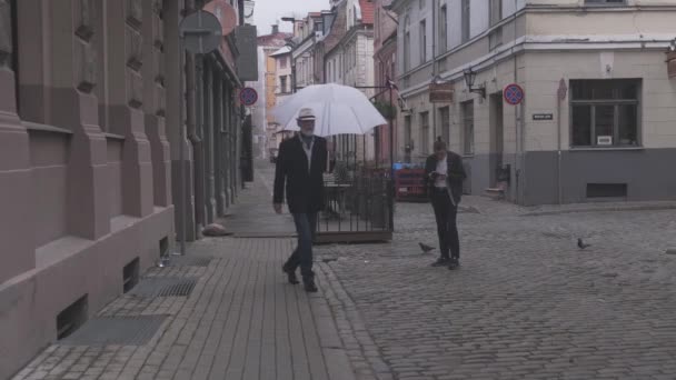 Mature person with open umbrella walks along city street — Stock Video