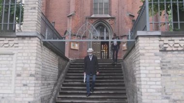 Adam video çekerken kıdemli adam kilisenin yanındaki merdivenlerden iniyor.