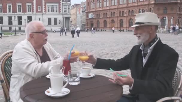 Счастливые взрослые мужчины звонят в стаканы с коктейлями в уличном кафе — стоковое видео