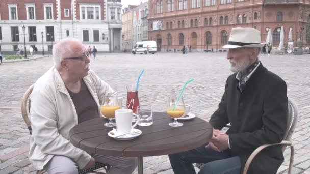 Пухнастий пенсіонер переговори з другом за столом у вуличному кафе — стокове відео