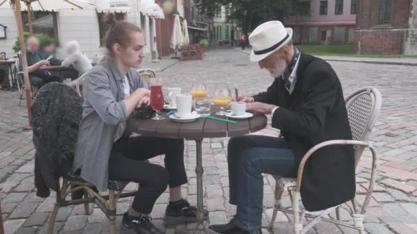 Senior muž píše a cinká sklenice s hipsterem v kavárně — Stock video