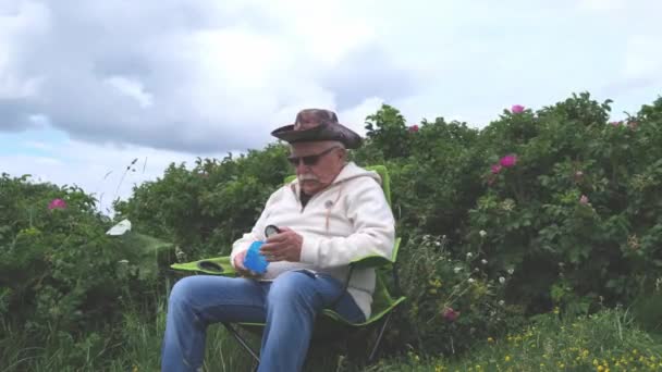 Viejo con bigote saca lupa cerca de los arbustos — Vídeos de Stock