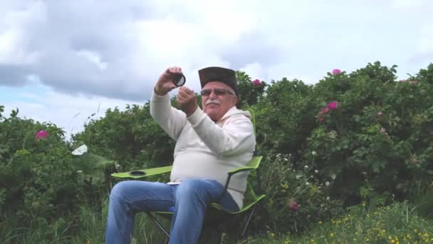 Senior schaut durch Lupe in der Nähe von Büschen — Stockvideo