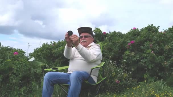 Starší osoba se dívá přes lupu v zahradě — Stock video