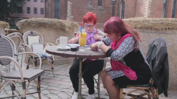 当朋友在咖啡店填表时，老年妇女调整围巾 — 图库视频影像