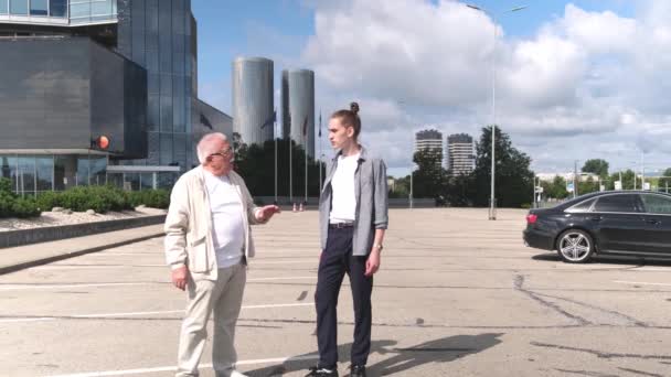 Mature homme parle à jeune gars marchant le long du site de stationnement — Video