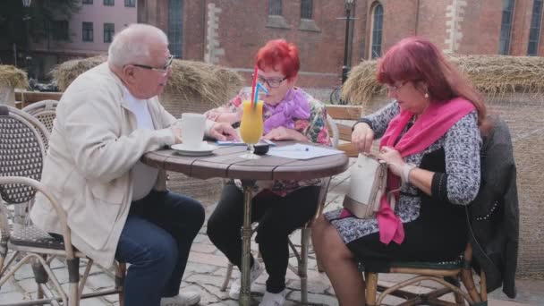 Reife Frau wühlt bei Tisch mit Freunden in Handtasche — Stockvideo